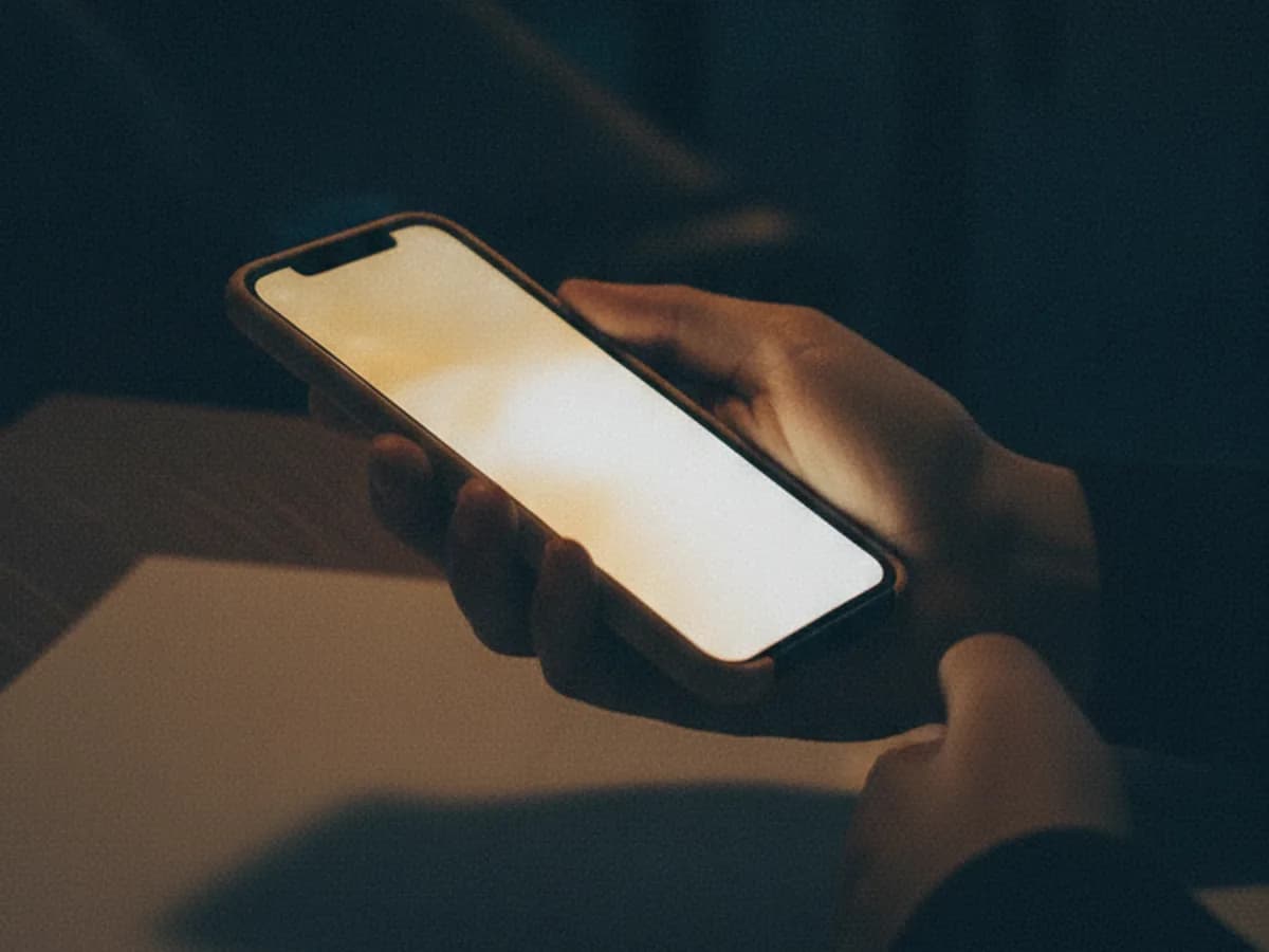 Hand hält Smartphone mit sanft leuchtendem, unscharfem Bildschirm